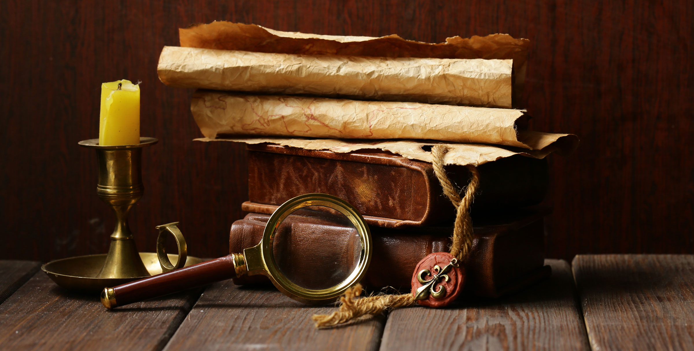 Old Scrolls, Books, and a Magnifying glass on a table.